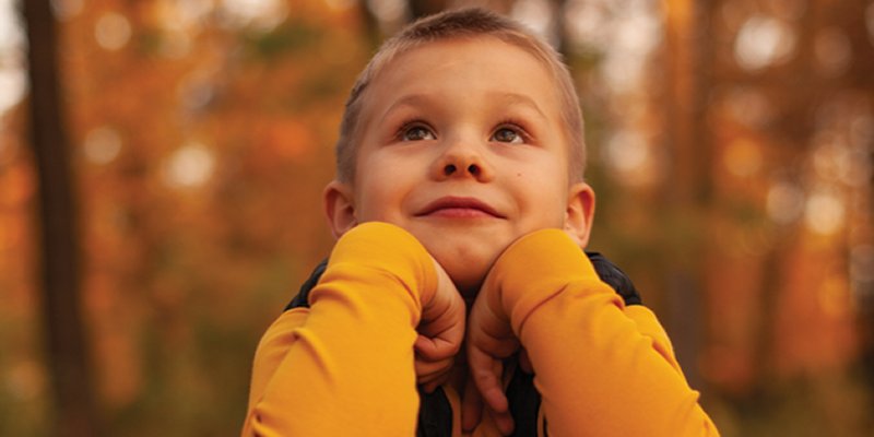 QFHSA Fall 2024 Newsletter - boy in the woods, crouching, elbows on knees.